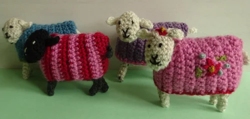 A group of small crochet sheep in bright colours.