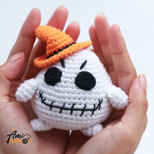 An amigurumi ghost with an orange witches hat.