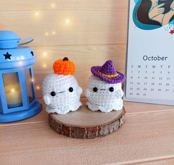 Two mini crochet ghosts wearing hats.