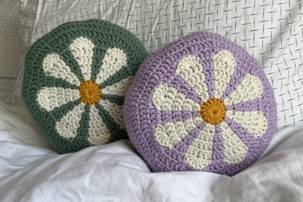 Two colourwork crochet circle cushions with floral motifs.