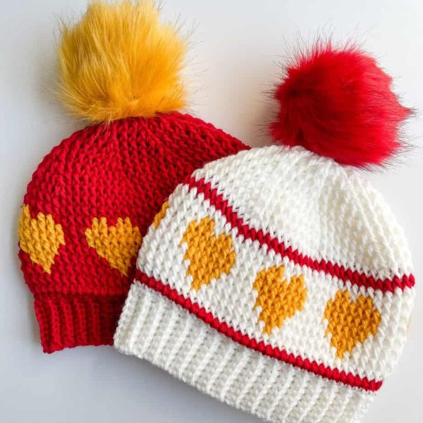 Two colorwork crochet hats with heart motifs.