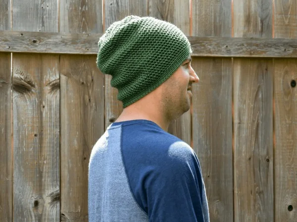 A man wearing a green crochet slouch hat.