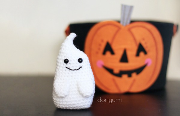 A white crochet ghost standig in front of a jack-o-lantern