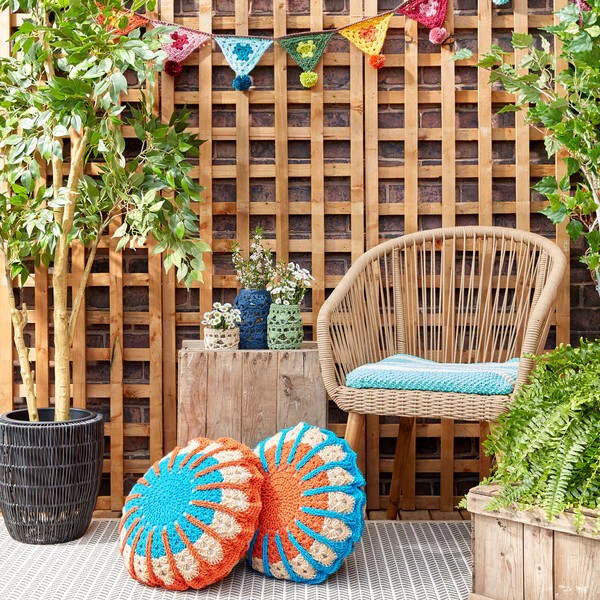 Colourful round crochet pillows in an outdoor patio setting.