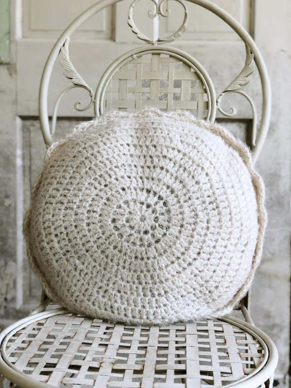 A simple, round crochet pillow on a chair.