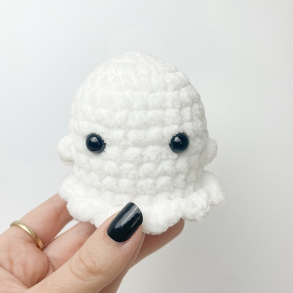 A mini crochet ghost made in chunky chenille-style yarn.