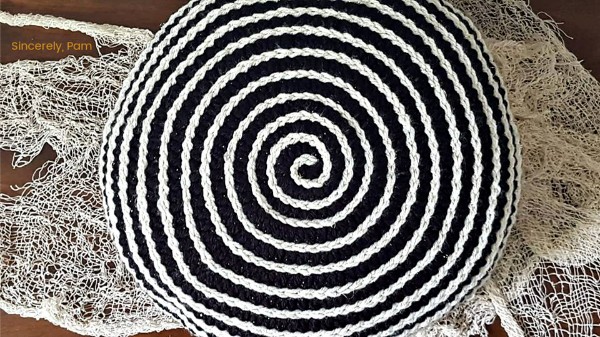 A black and white spiral crochet pillow.