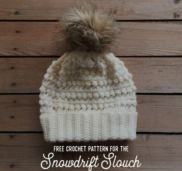 A cream coloured slouch crochet hat with faux fur pompom.