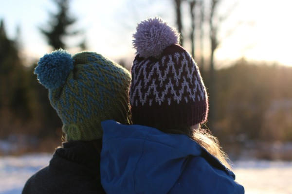 Back view of two people in crochet colourwork hats.