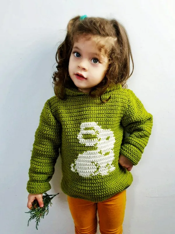 A child wearing a green crochet hoodie with a bunny motif.