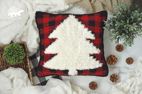 A buffalo-plaid crochet pillow with a faux fur Christmas tree motif.