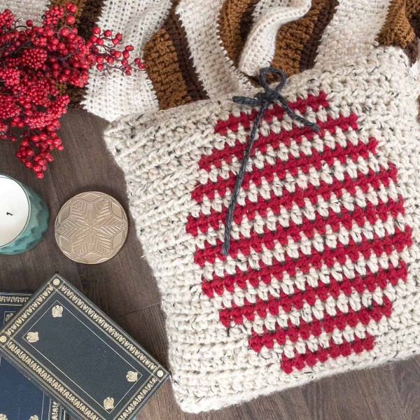 A simple red and white colourwork crochet pillow with a Christmas bauble motif.