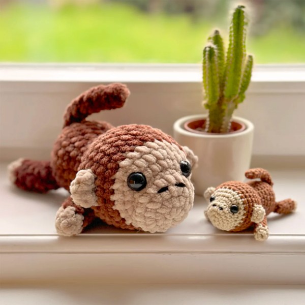 Two different sized crochet monkey toys on a window sill.