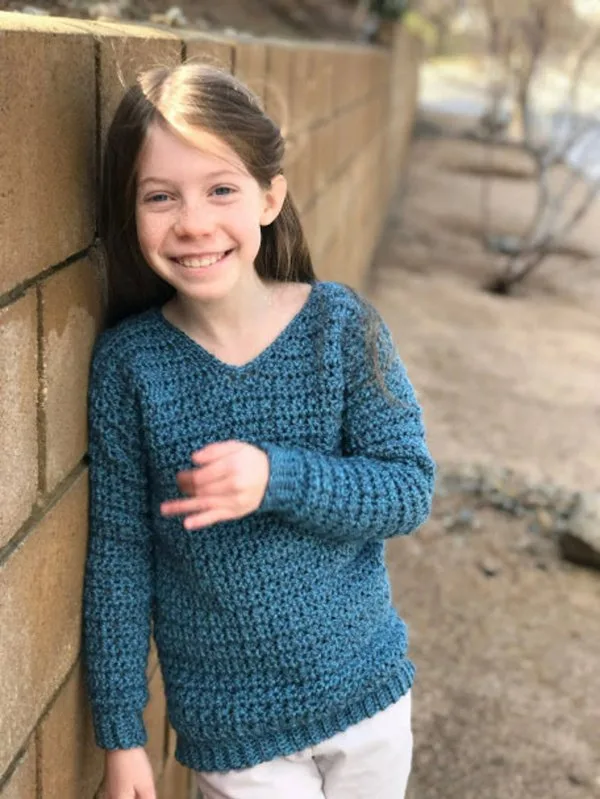 A child wearing a v-neck crochet sweater with a textured stitch.