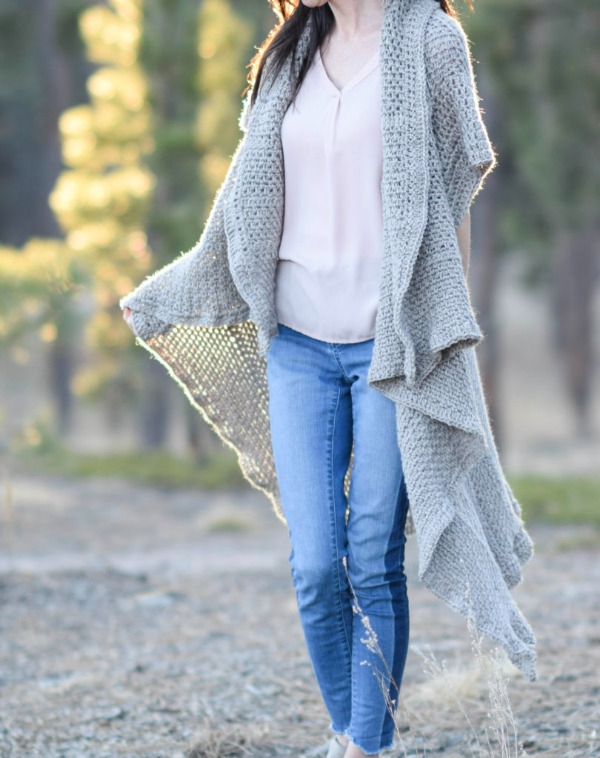 A long crochet duster with ruffled edges worn over jeans and a tee.