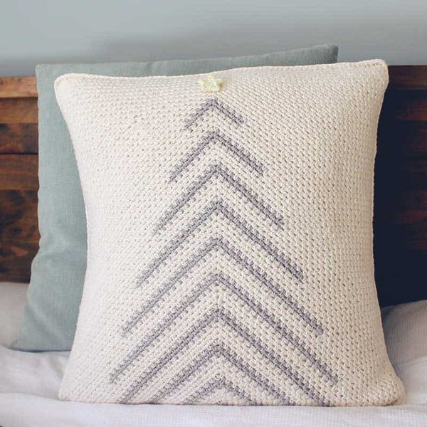 A modern crochet Christmas pillow with a Christmas tree motif in neutral colours.