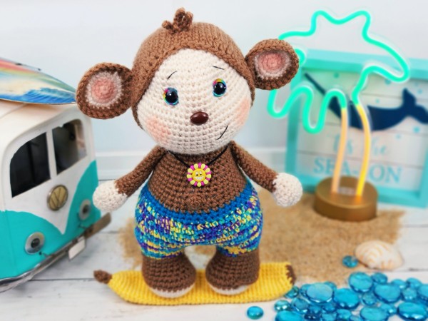 A cute crochet monkey on a surfboard.
