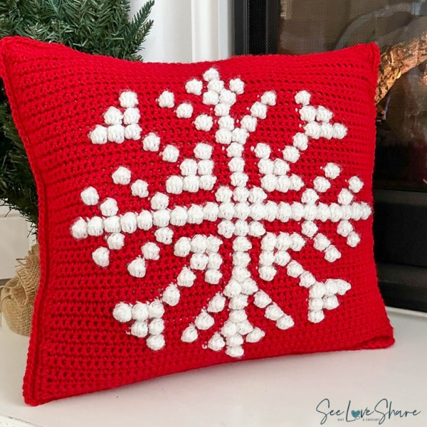 A red and white crochet pillow with a bobble stitch snowflake motif.