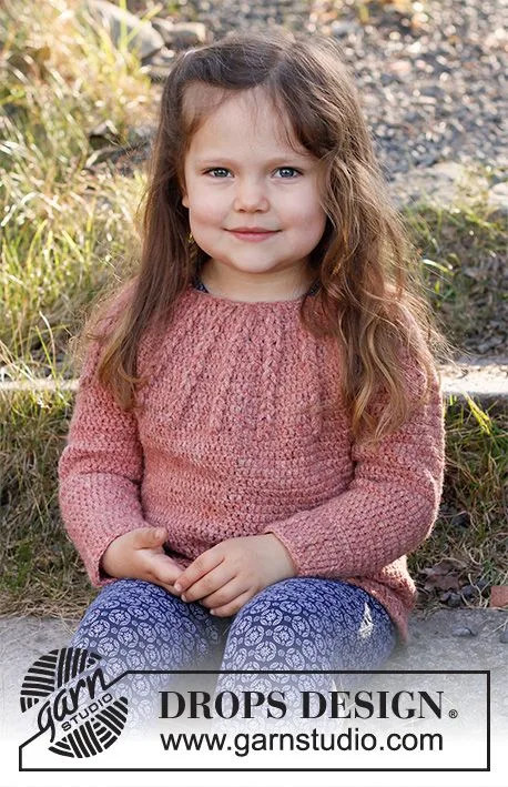 A young girl weraring a pink crochet sweater with a round yoke.