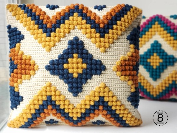 A geometric pattern bobble stitch crochet pillow featuring colourwork.