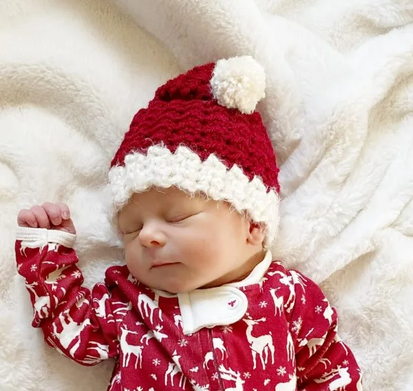 A baby wearing a red Santa hat.