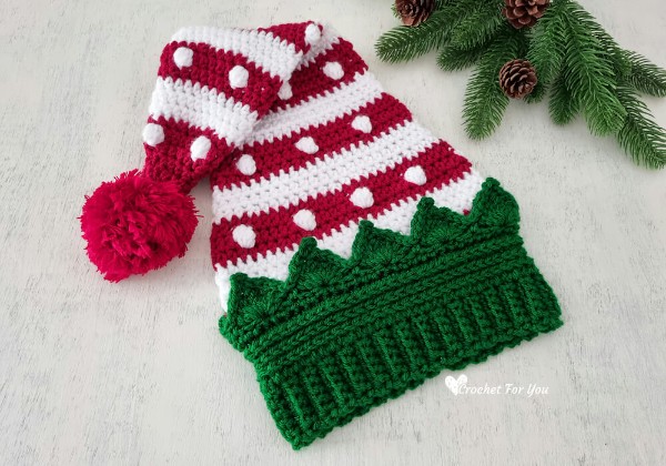A striped crochet Christmas hat with a green crown shaped brim.