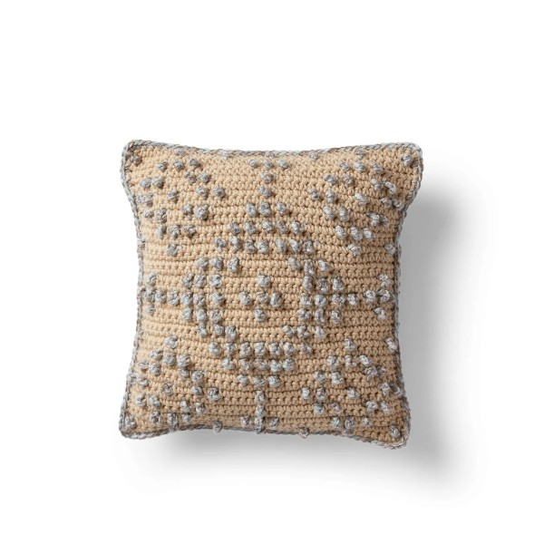 A textured, geometric patterned crochet pillow cover.