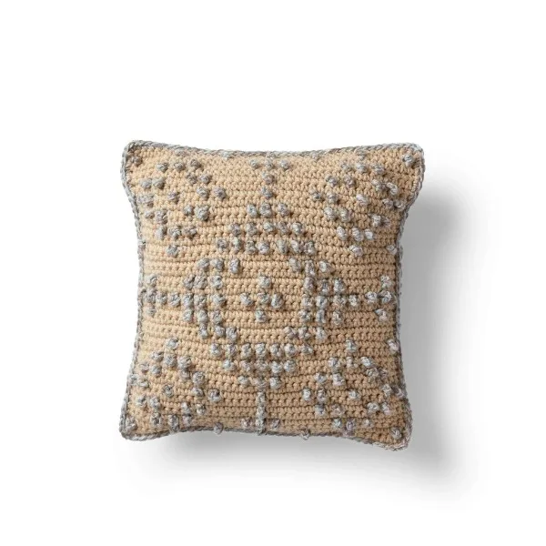 A textured,  geometric patterned crochet pillow cover.