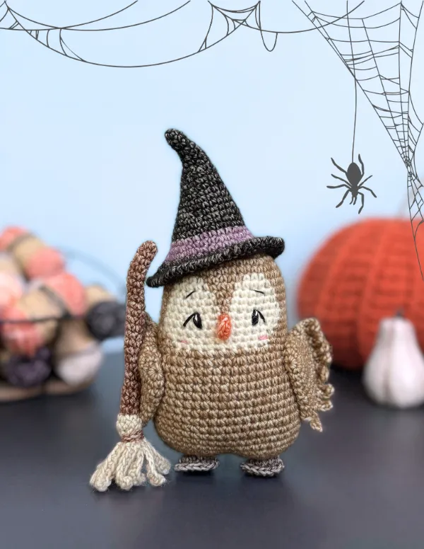 A crochet owl with a witches hat and broom.