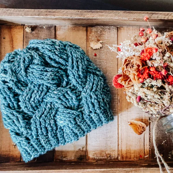 Blue crochet kids' beanie featuring cable stitch.