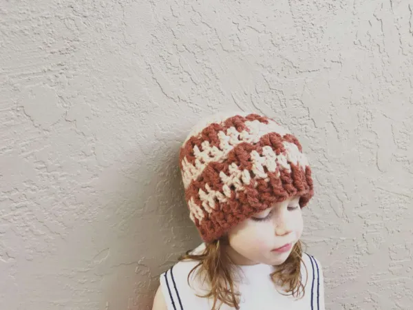 A young child wearing a striped crochet beanie.