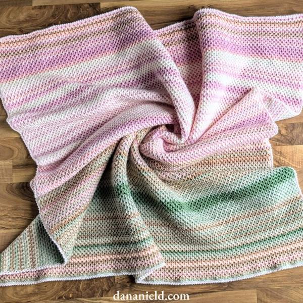 A pastel-toned temperature blanket crocheted in the honeycomb stitch.