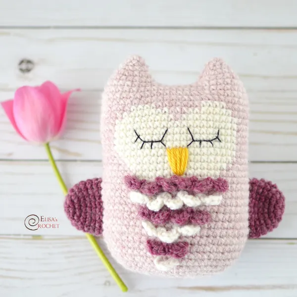 A pastel-pink crocheted owl toy.