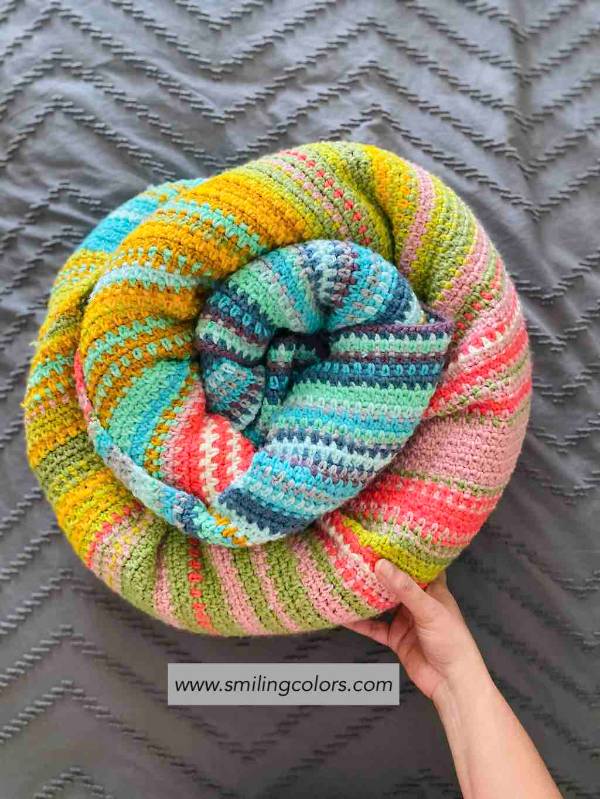 A pictured of a colourful temperature blanket, rolled up in a coil.