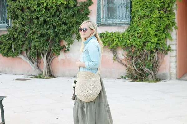 A woman with a large, raffia crochet circle bag with tassels.