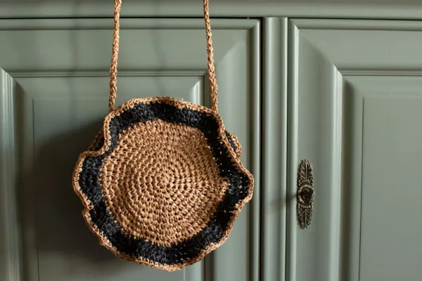 A small crochet circle bag with a ruffled edge.