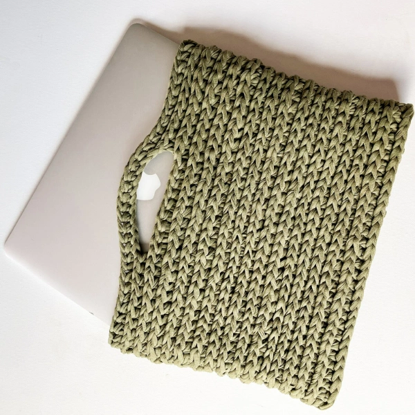 A macbook air in a green crochet laptop bag.