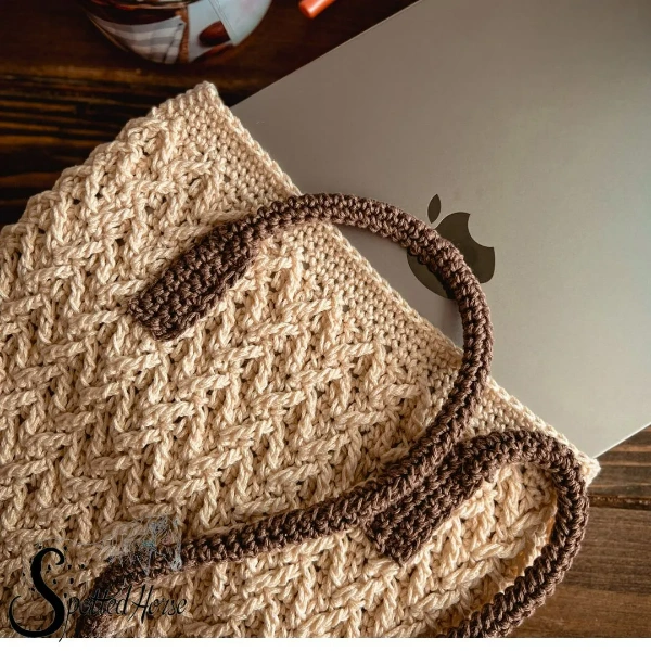 A textured crochet laptop bag with long handles.