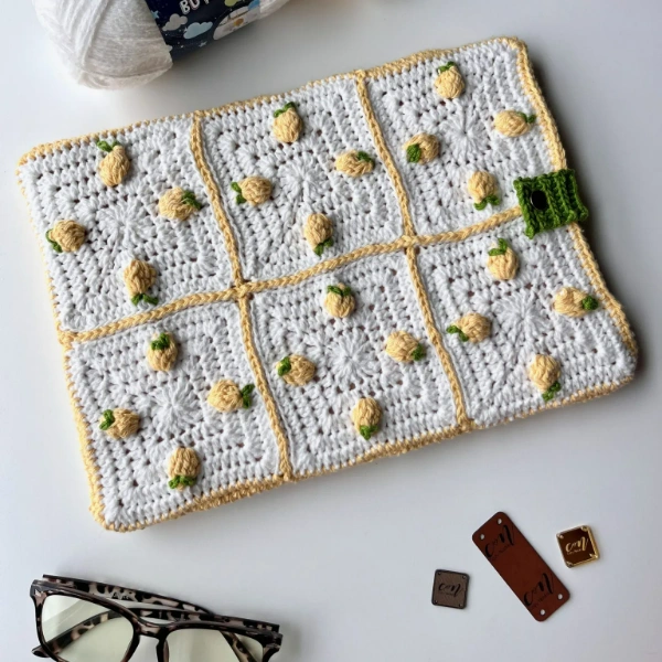 A laptop sleeve with cute lemon-themed crochet granny square design.