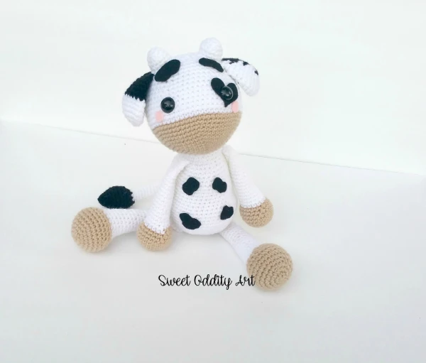 A black and white crochet cow plushie.