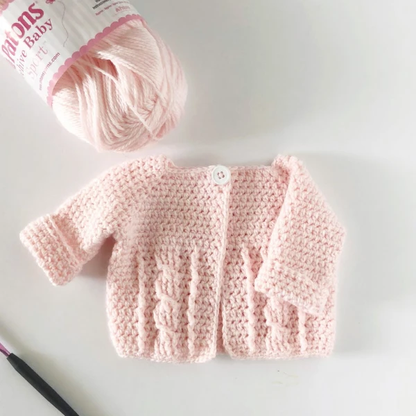 Soft pink cable crochet baby sweater.