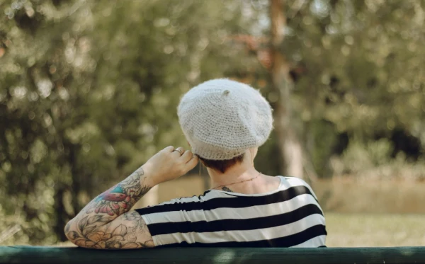 Back view of a tattooed woman wearing a french-style crochet beret