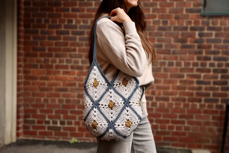 A woman waering a granny square tote bag over her shoulder.