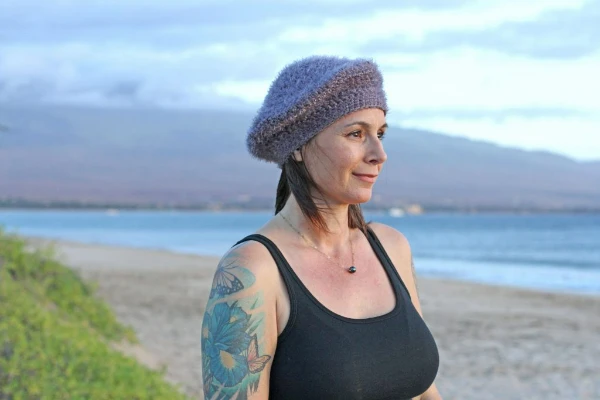 A woman at the beach wearing a crocheted beret.
