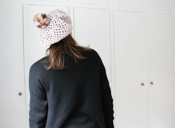 A woman wearing a crochet beret with a pompom.
