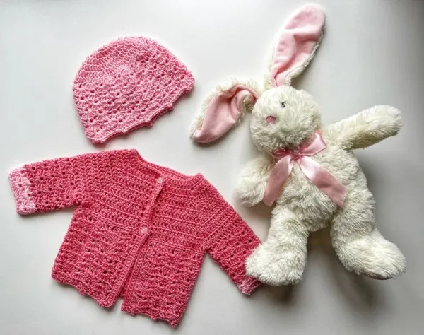 Bright pink newborn crochet cardigan and matching bonnet.