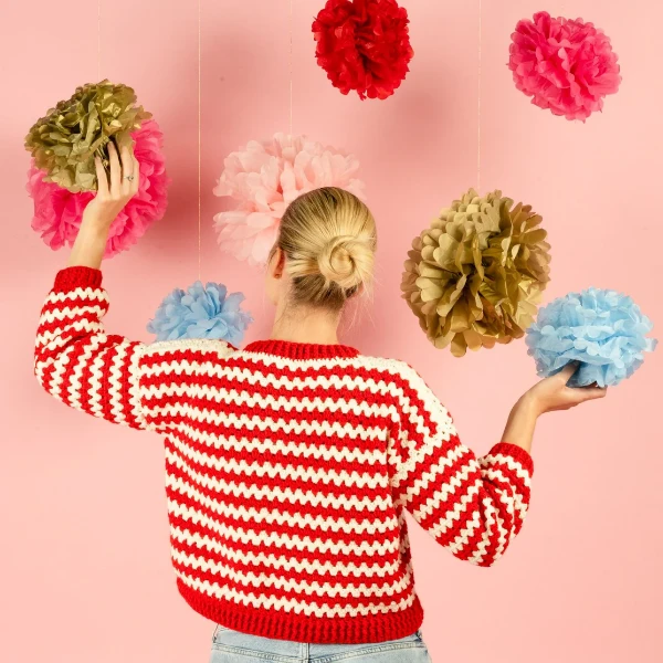 A crochet Christmas sweater made with red and white granny stitch stripes.