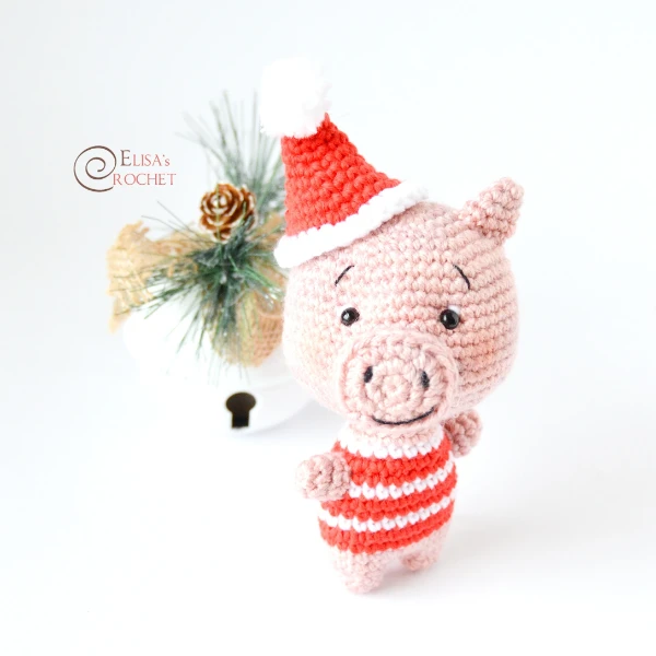 A crocht pig amigurumi wearing a Chrismas sweater and hat.