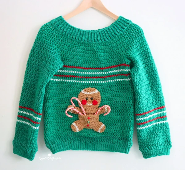 A green crochet sweater with a gingerbread man applique.