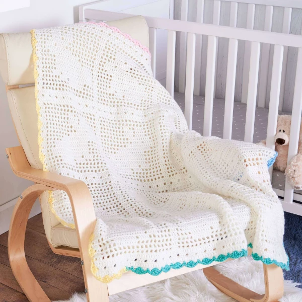 A white, filet crochet baby blanket with bunny motifs.